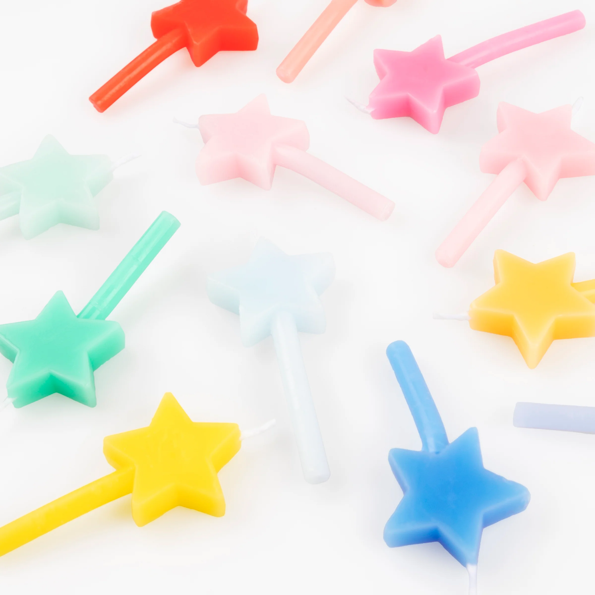 Close-up view of colorful star-shaped birthday candles scattered across a white background.