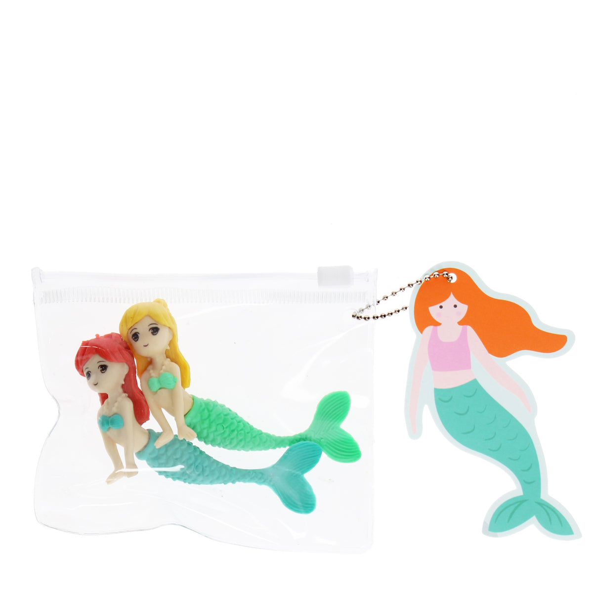 Two small mermaid figurines, one with red hair and the other blonde, lie inside a clear pouch. A cartoon mermaid keychain with orange hair hangs beside it.