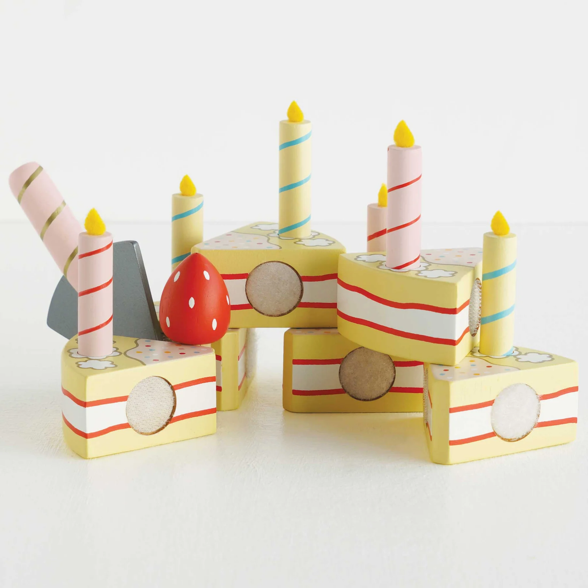 Wooden sliceable toy birthday cake with candles and strawberry.
