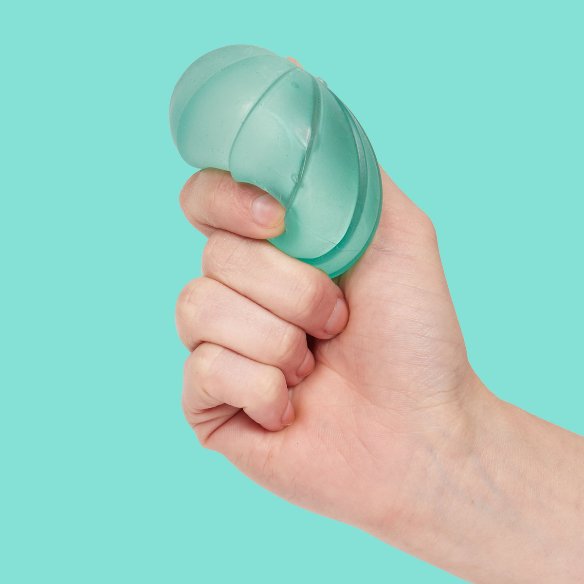 A hand is squeezing a translucent, green gel stress ball against a solid turquoise background, conveying a sense of tension relief and focus.