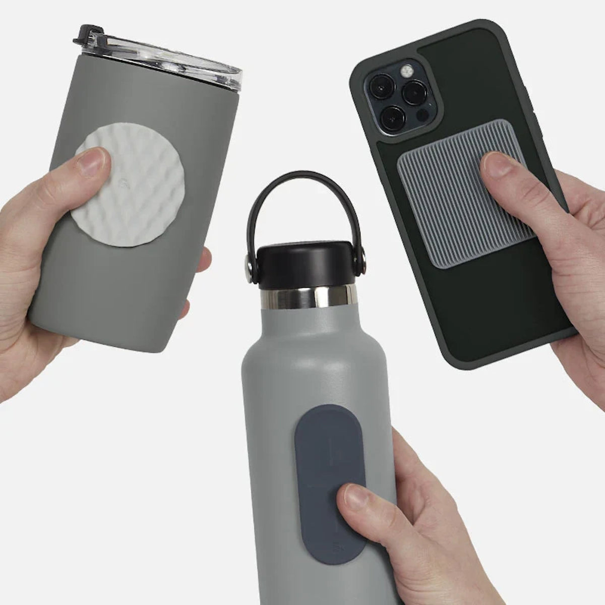 Three hands holding items with silicone sensory stickers on a grey travel mug, bottle, and phone.