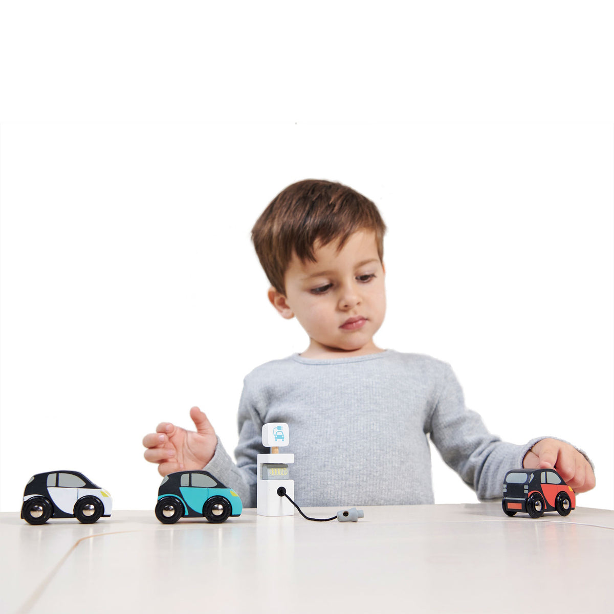 Young boy playing with a wooden car set and charging station.