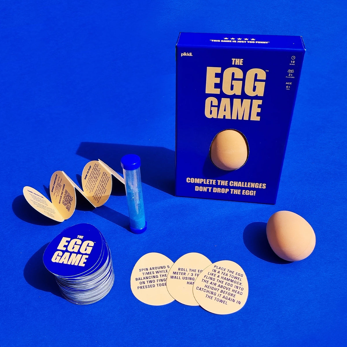 "The Egg Game" box displayed with toy egg, hourglass, folded instructions, and egg-shaped cards.