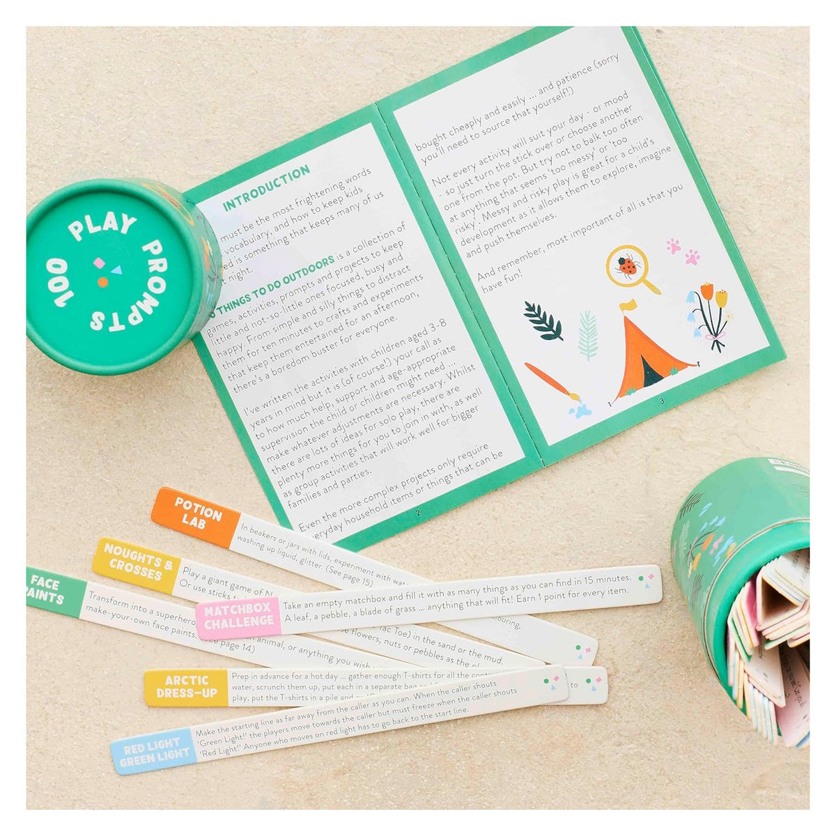 Open "100 Play Prompts" activity set with an instruction booklet, circular box, and colorful wooden sticks.