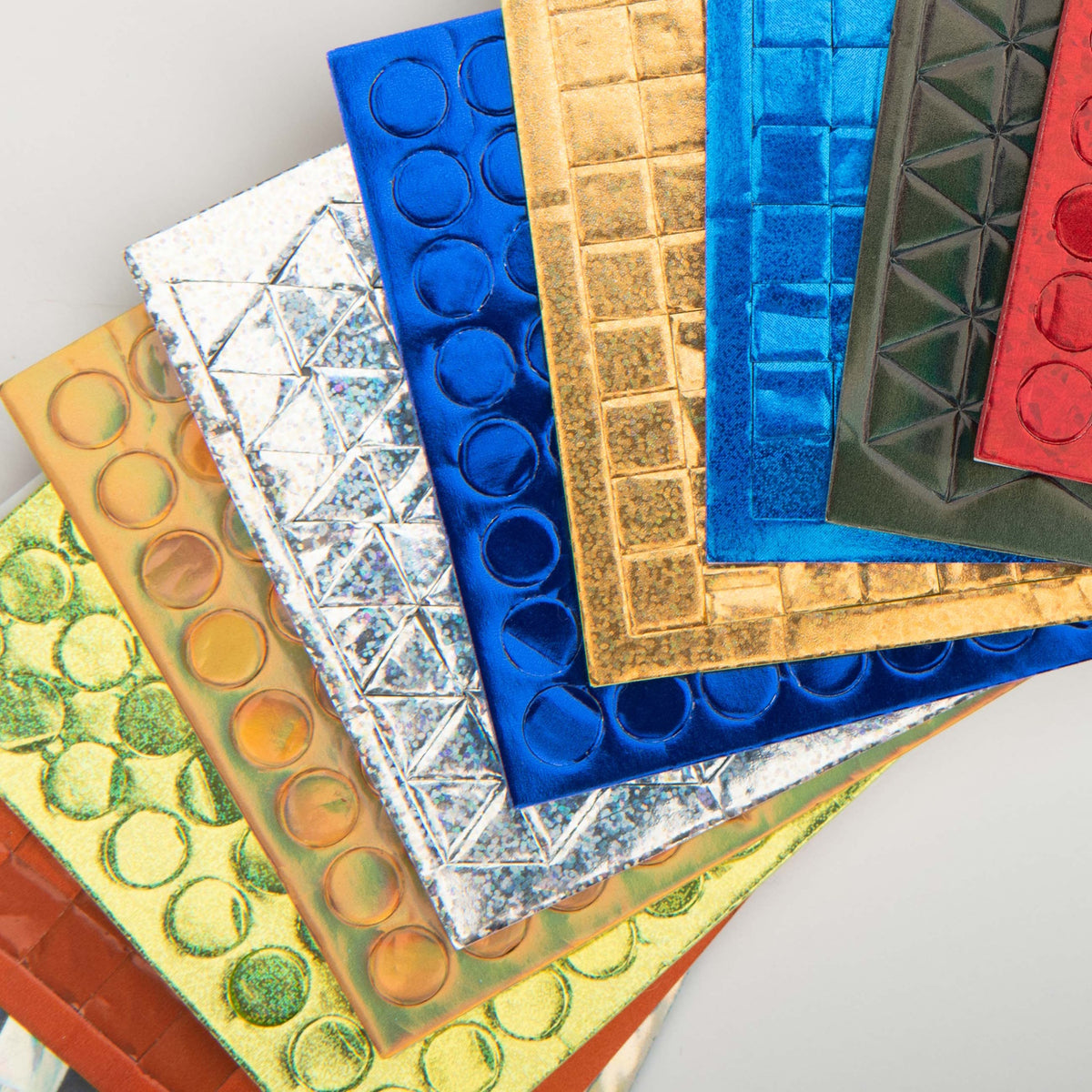 Close-up of metallic mosaic sticker sheets in various colors and geometric shapes for craft projects.