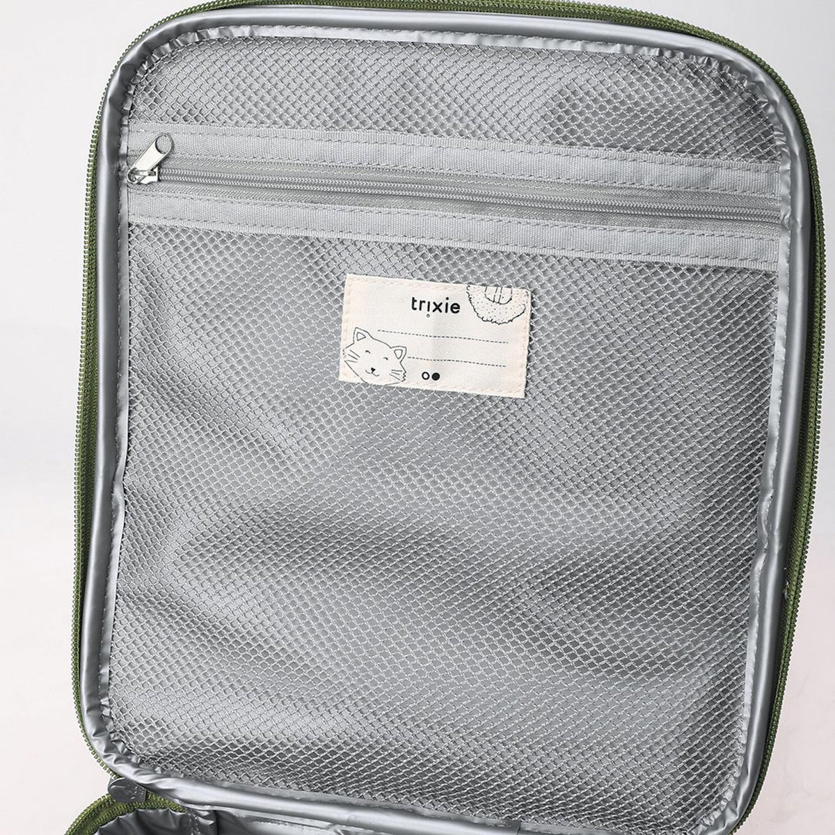 Close-up of the inside flap of a lunch bag, featuring a zippered grey mesh pocket and a name label.