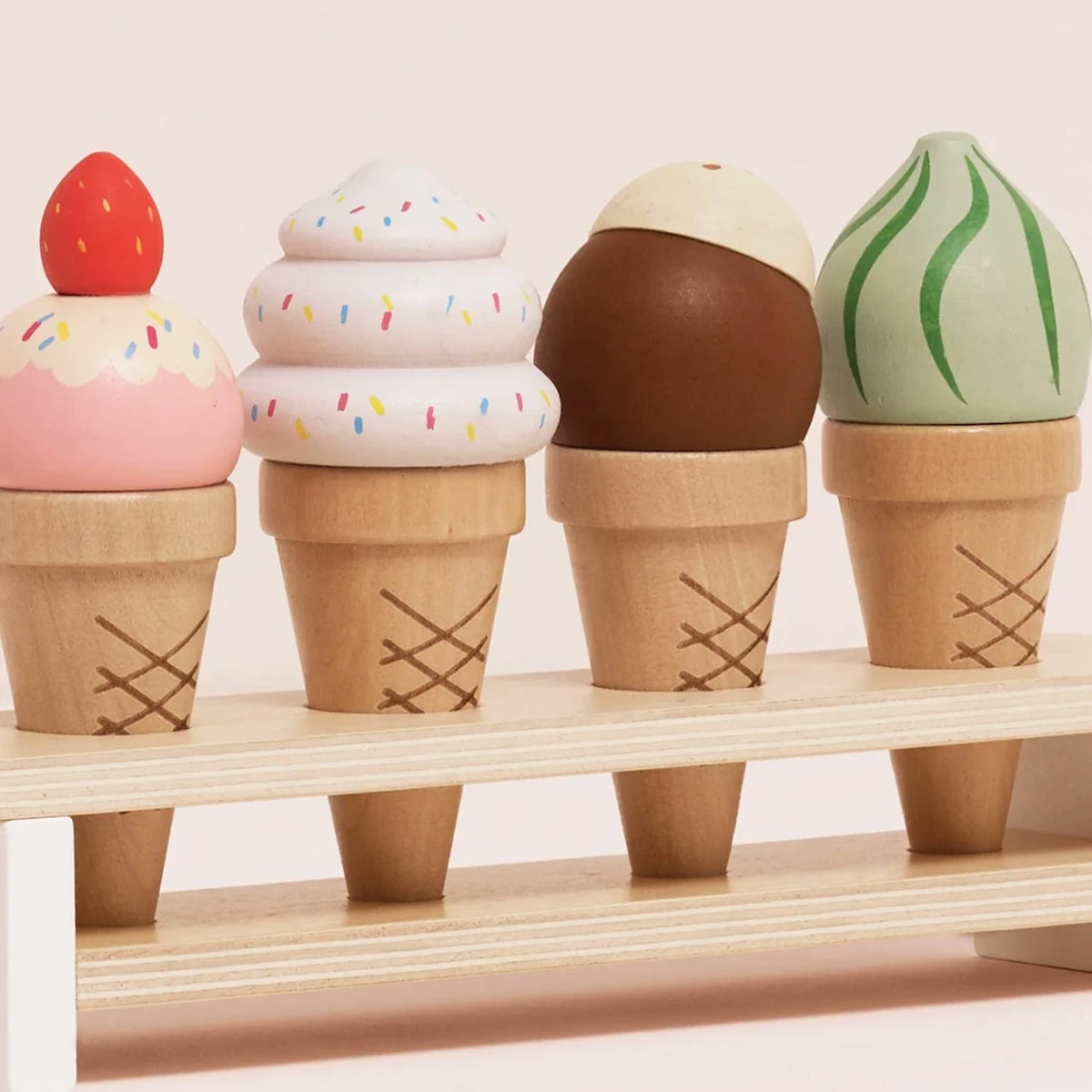 Close-up of four wooden toy ice cream cones in a wooden stand.