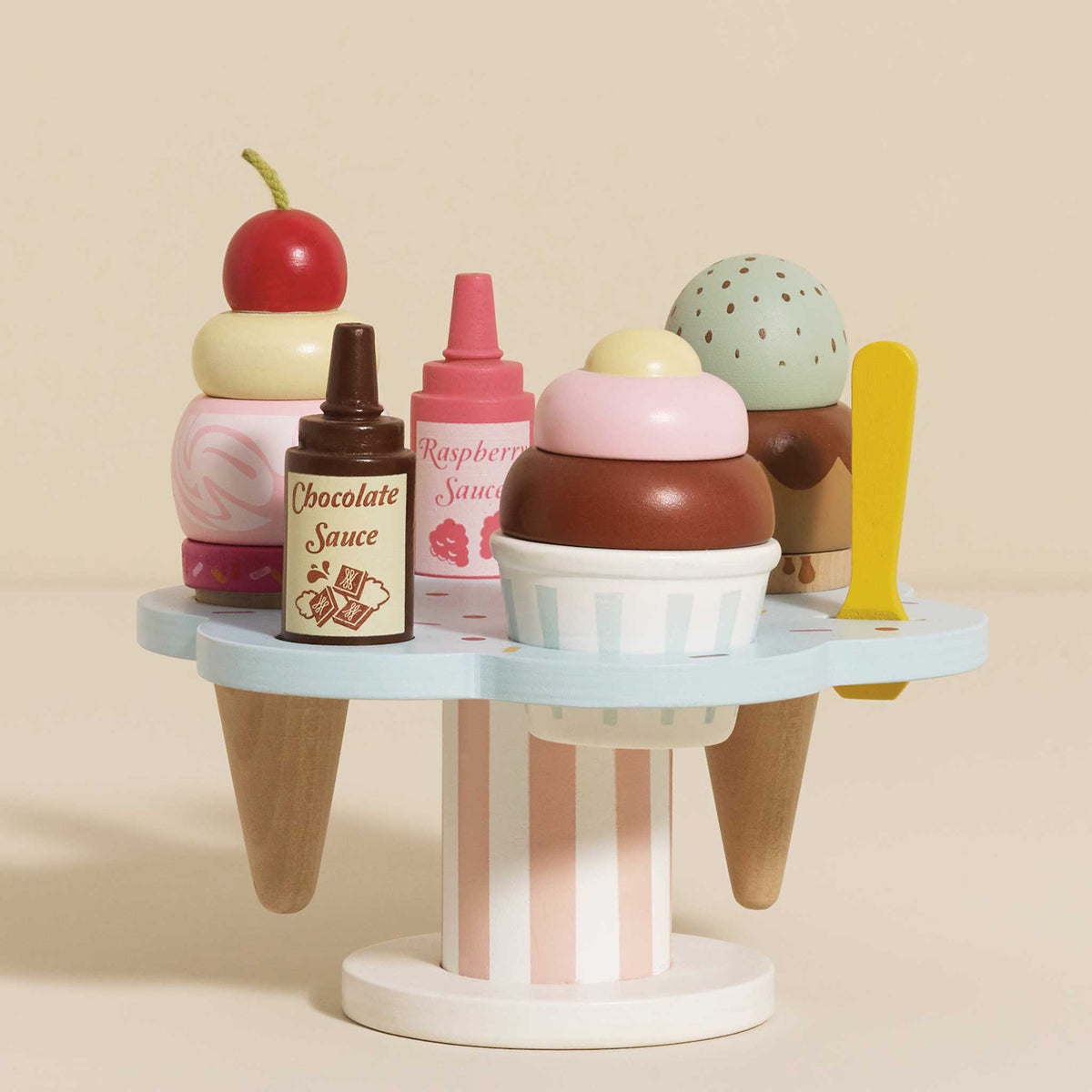 Wooden toy ice cream stand filled with stacked cones, sauce bottles, and colorful scoops.