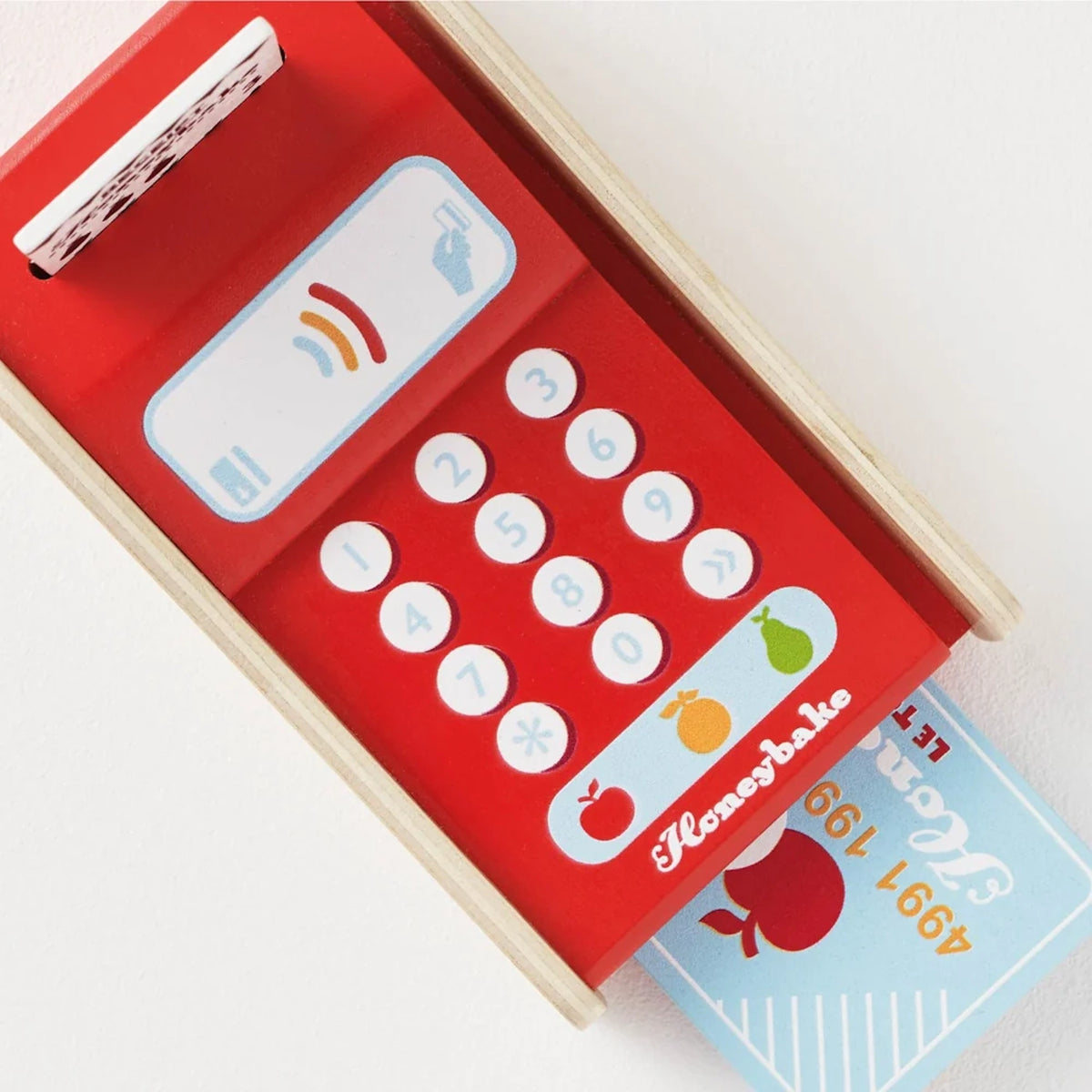 Top-down view of a red wooden toy card machine with buttons, a receipt, and a blue payment card inserted.