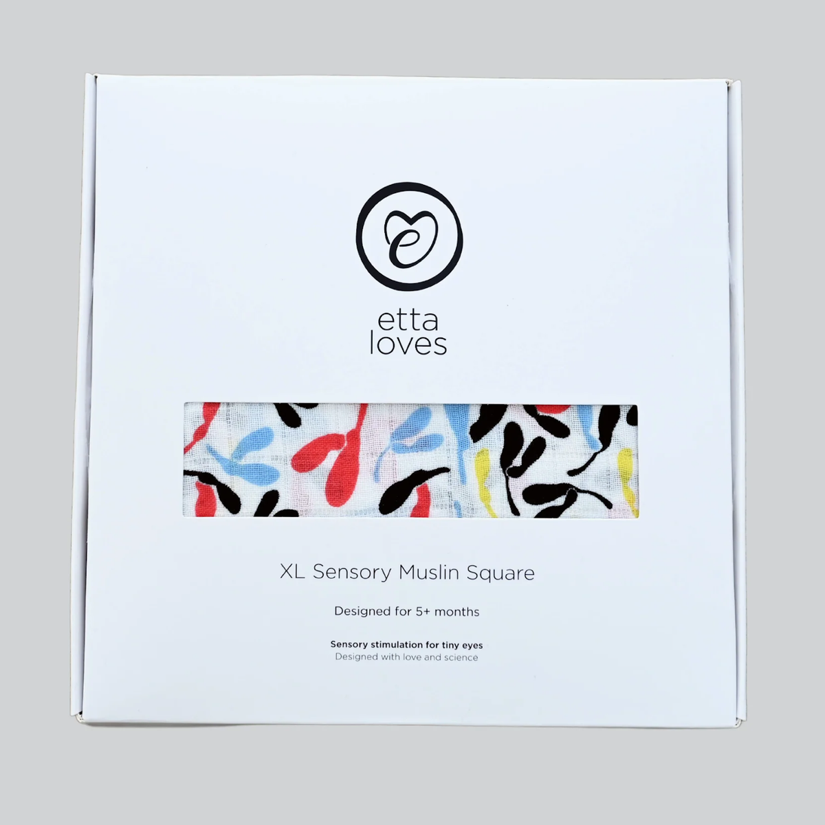 White Etta Loves box for XL Sensory Muslin Square with a window showing colorful pattern fabric.