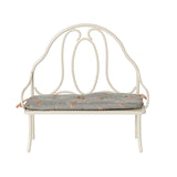 A front-facing view of the Maileg vintage-style bench in off white, highlighting its intricate metalwork and attached blue floral cushion.