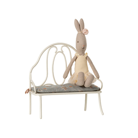 A Maileg rabbit sitting on the off-white vintage metal bench, showcasing its elegant design and soft blue floral cushion.