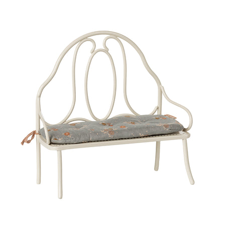 A charming Maileg vintage-style metal bench in off white, featuring a delicate blue floral-patterned cushion tied to the back poles.