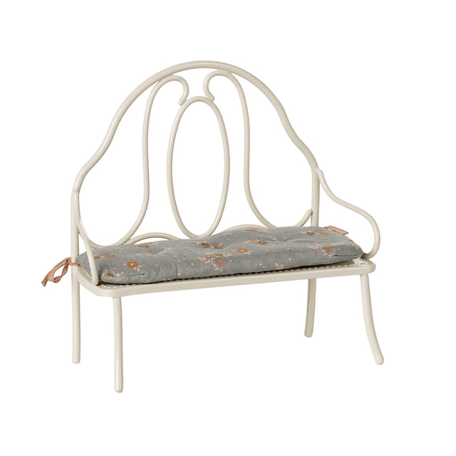 A charming Maileg vintage-style metal bench in off white, featuring a delicate blue floral-patterned cushion tied to the back poles.