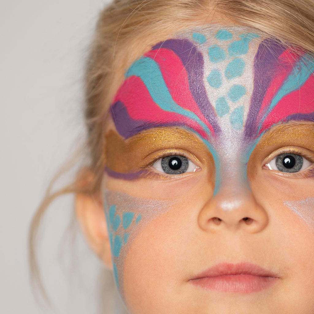 A close-up of a child with intricate butterfly face paint in shades of pink, purple, and gold, creating a delicate winged effect.