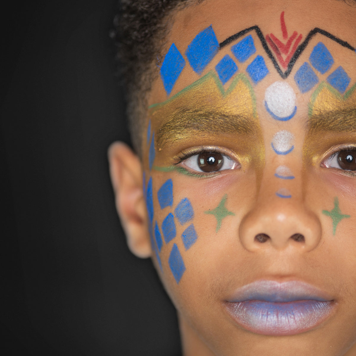 A child with intergalactic-themed face paint, including blue and gold patterns with starry details.