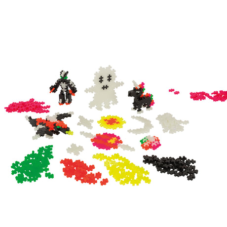 Assorted Plus-Plus Build & Glow pieces, including a glow-in-the-dark ghost, robot, flying creature, and small unicorn.