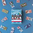 Londji Penguins & Friends Domino box with scattered game pieces – The game box in the centre, surrounded by various animal domino tiles.