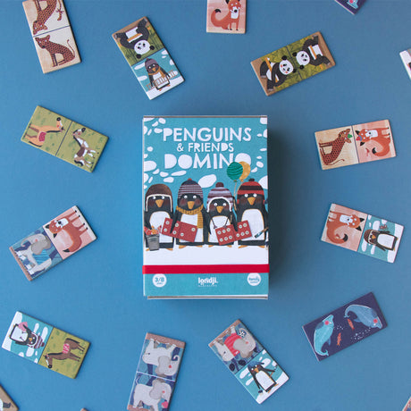 Londji Penguins & Friends Domino box with scattered game pieces – The game box in the centre, surrounded by various animal domino tiles.