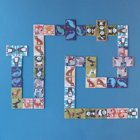 Penguins & Friends Domino pieces laid out in play – A set of beautifully illustrated animal domino pieces arranged in a game formation on a blue surface.