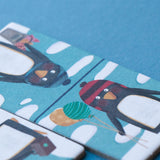 Close-up of Londji domino pieces featuring penguins in winter gear – Two domino tiles featuring adorable penguins in warm scarves and hats.