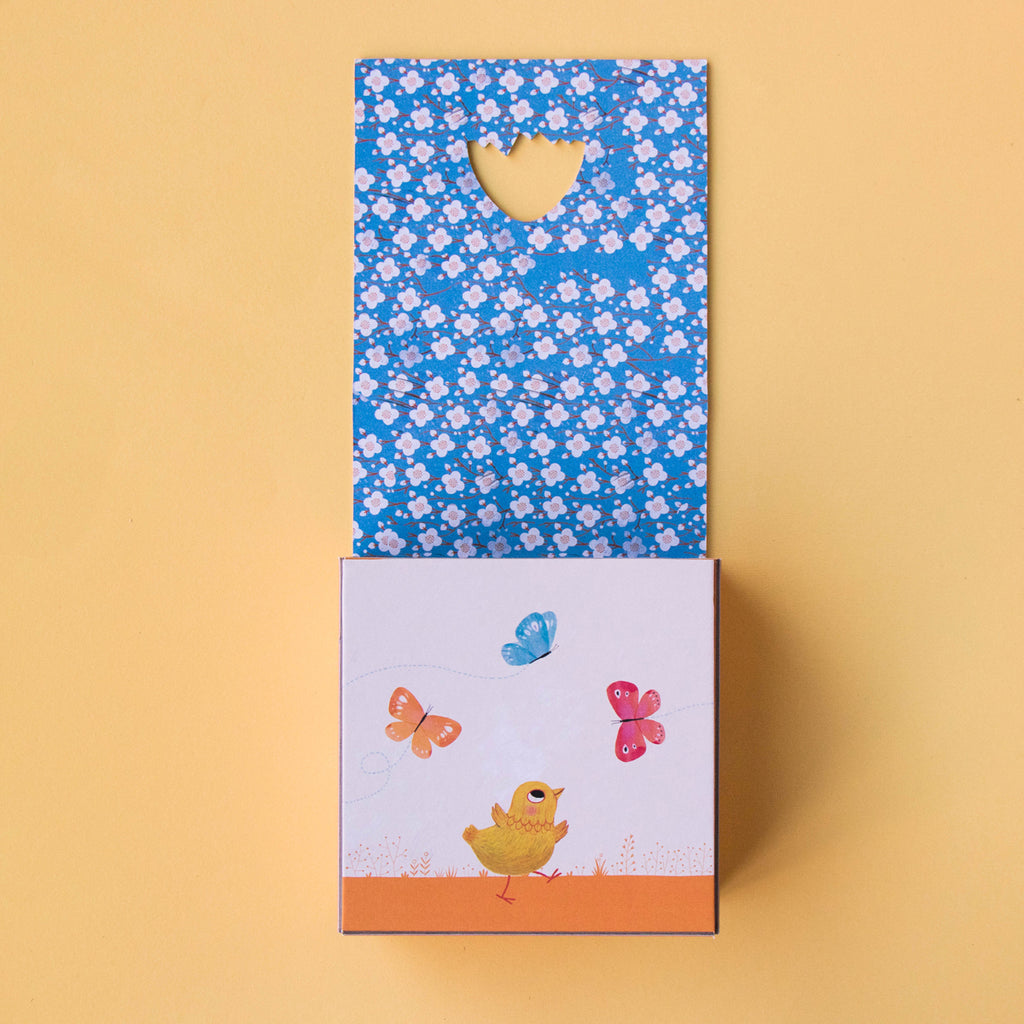 Opened game box revealing a colourful floral pattern and a chick illustration.