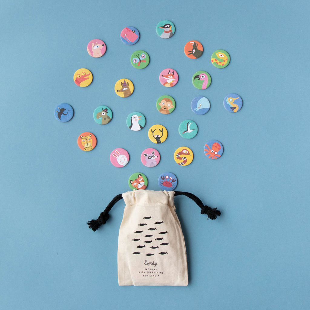Fabric storage pouch for Lotto Habitats game – A drawstring pouch with a fish pattern and black ties, surrounded by scattered animal tokens.