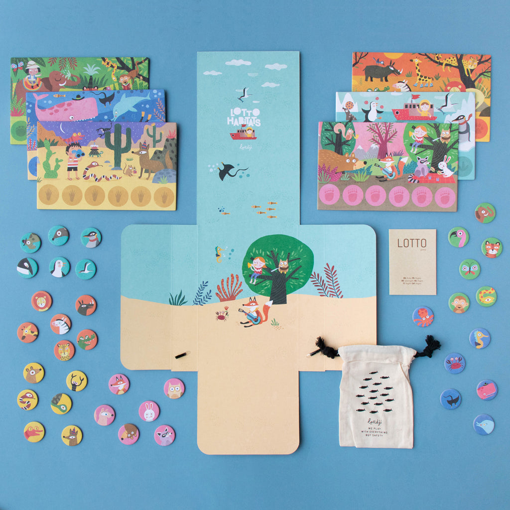 Flat lay of Lotto Habitats board game – A colourful board game featuring illustrated animal habitat boards, round animal tokens, and a fabric storage pouch.
