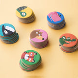 Stacks of animal tokens for Lotto Habitats game – Close-up of wooden animal tokens featuring vibrant illustrations of animals such as a tiger, crocodile, bear, and lizard.