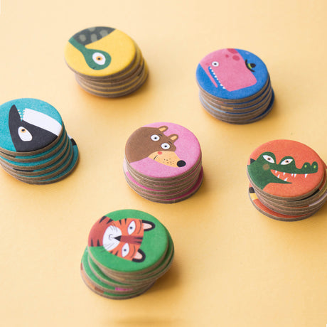 Stacks of animal tokens for Lotto Habitats game – Close-up of wooden animal tokens featuring vibrant illustrations of animals such as a tiger, crocodile, bear, and lizard.