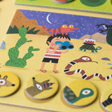 Desert habitat board from Lotto Habitats game – A child with binoculars explores the desert, surrounded by illustrated desert creatures like snakes and lizards.