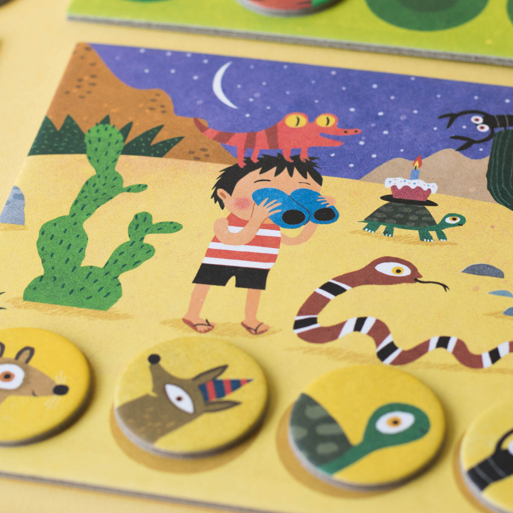 Desert habitat board from Lotto Habitats game – A child with binoculars explores the desert, surrounded by illustrated desert creatures like snakes and lizards.