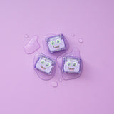 Three purple Lumi Glo Pals light-up cubes on a lilac background with water droplets.