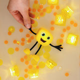  A yellow Glo Pals Alex character floating in water with glowing yellow light-up cubes and scattered yellow confetti.