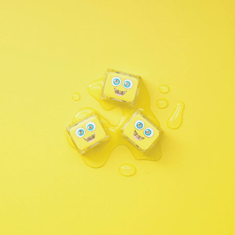Three yellow Glo Pals light-up cubes on a vibrant yellow surface with water droplets.