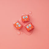 Three Glo Pals Sammy light-up cubes on a pink background with water droplets