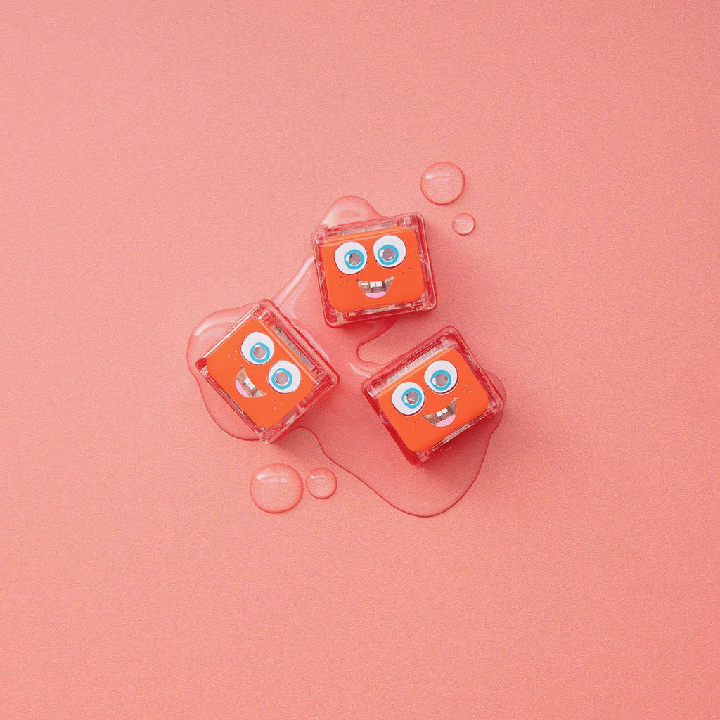Three Glo Pals Sammy light-up cubes on a pink background with water droplets