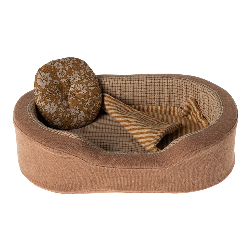 The image shows a soft toy dogs bed in brown, with a pillow and blanket on a white background.