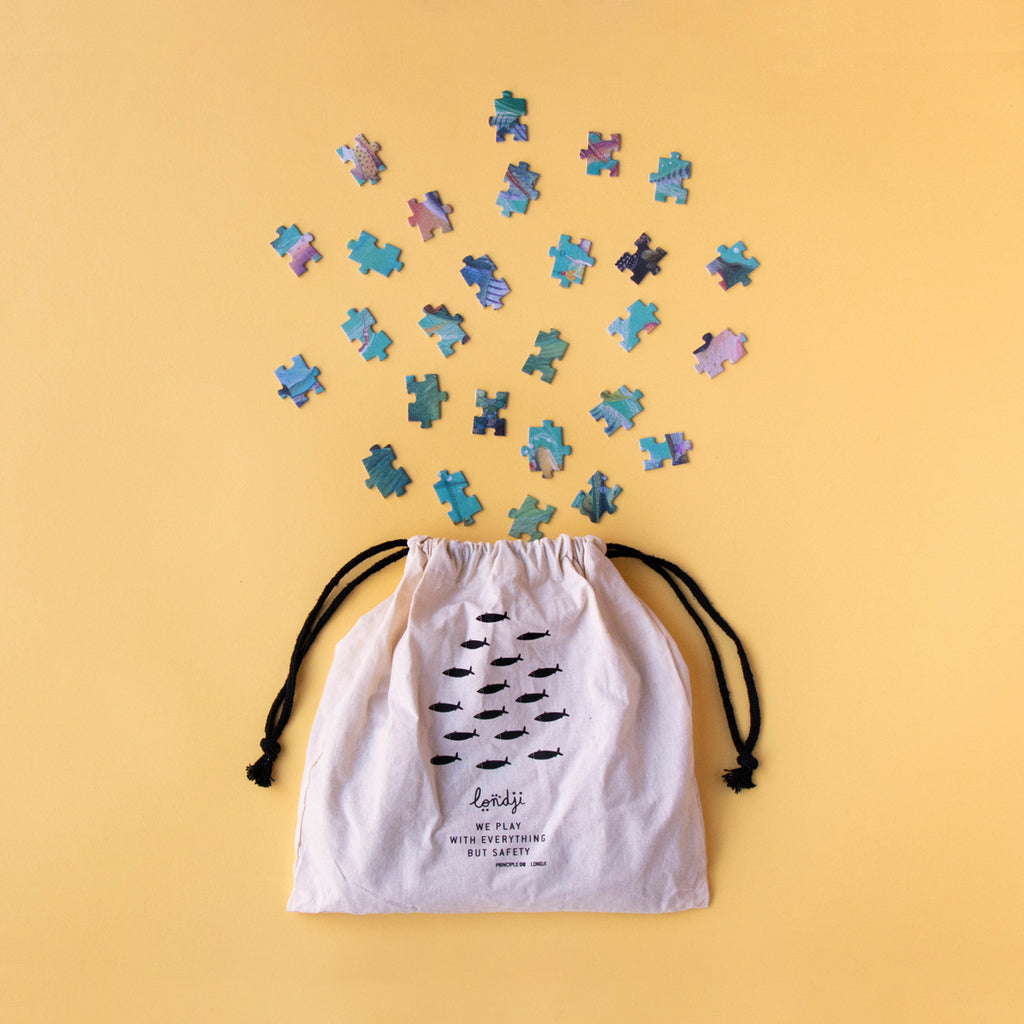 A charming arrangement of puzzle pieces spilling from a fabric storage bag onto a yellow background.