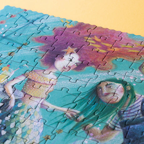 A close-up of a mermaid illustration on the puzzle, showing glitter details in her flowing pink hair.