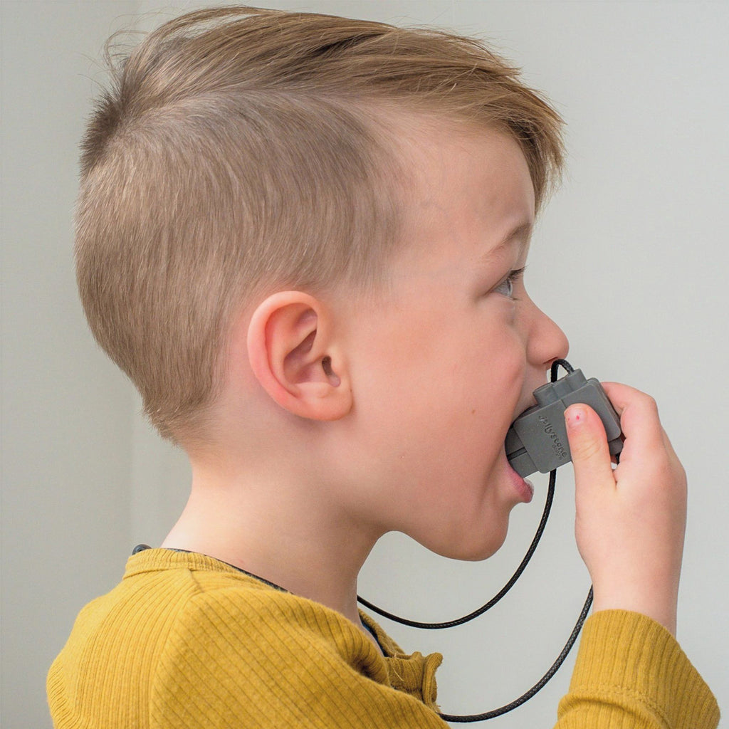 Child wearing a mustard yellow top, chewing on a Jellystone Designs robot pendant.