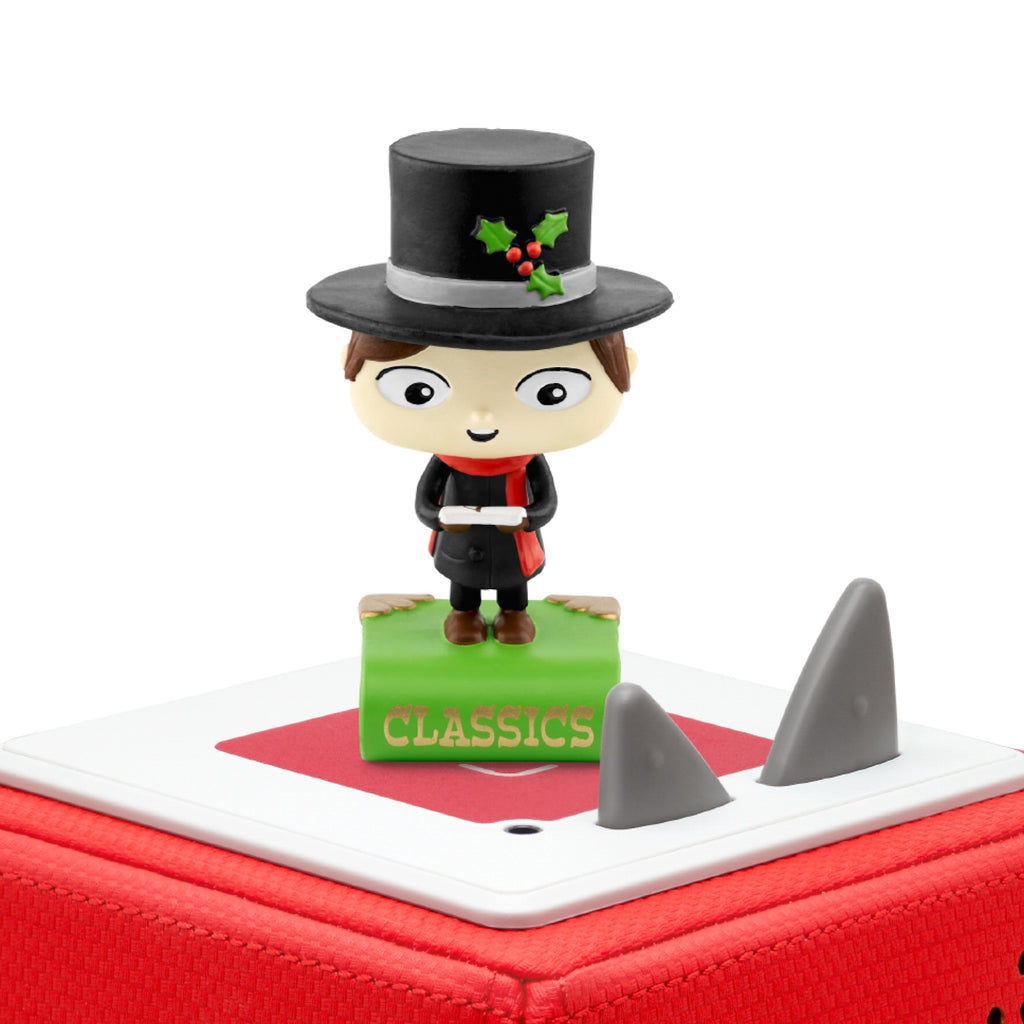 A cheerful figurine of a child in a top hat and red scarf stands on a green book labeled "CLASSICS".
