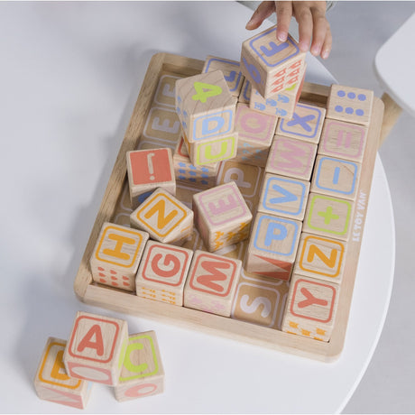 Child's hand placing pastel wooden alphabet blocks onto a storage tray.