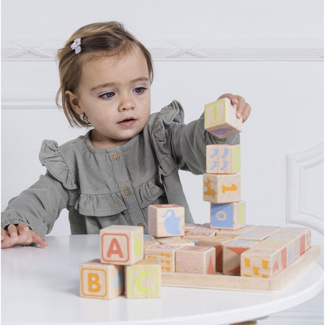 Toddler playing with and stacking wooden ABC learning blocks at a white table.