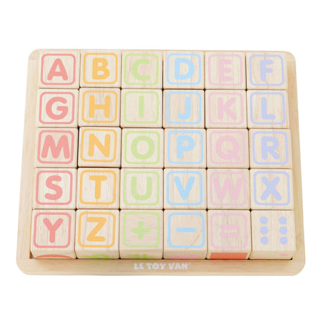 Wooden alphabet blocks set with pastel letters and math symbols displayed on a wooden tray.
