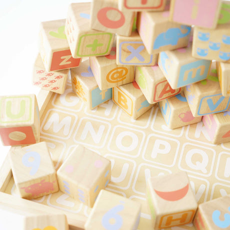 Stacked wooden alphabet and number learning blocks scattered across a matching tray base.