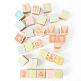 Wooden ABC learning blocks arranged on white background spelling simple words and math equations.