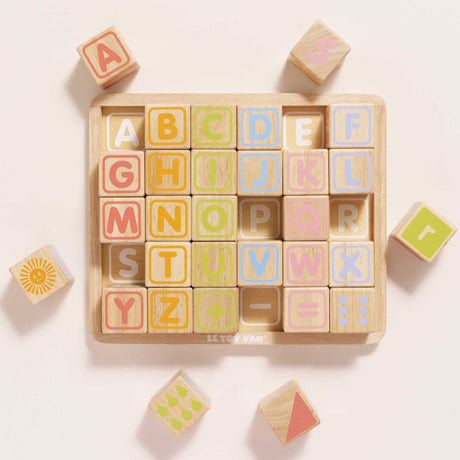 Wooden ABC learning blocks in a tray with loose blocks surrounding it.