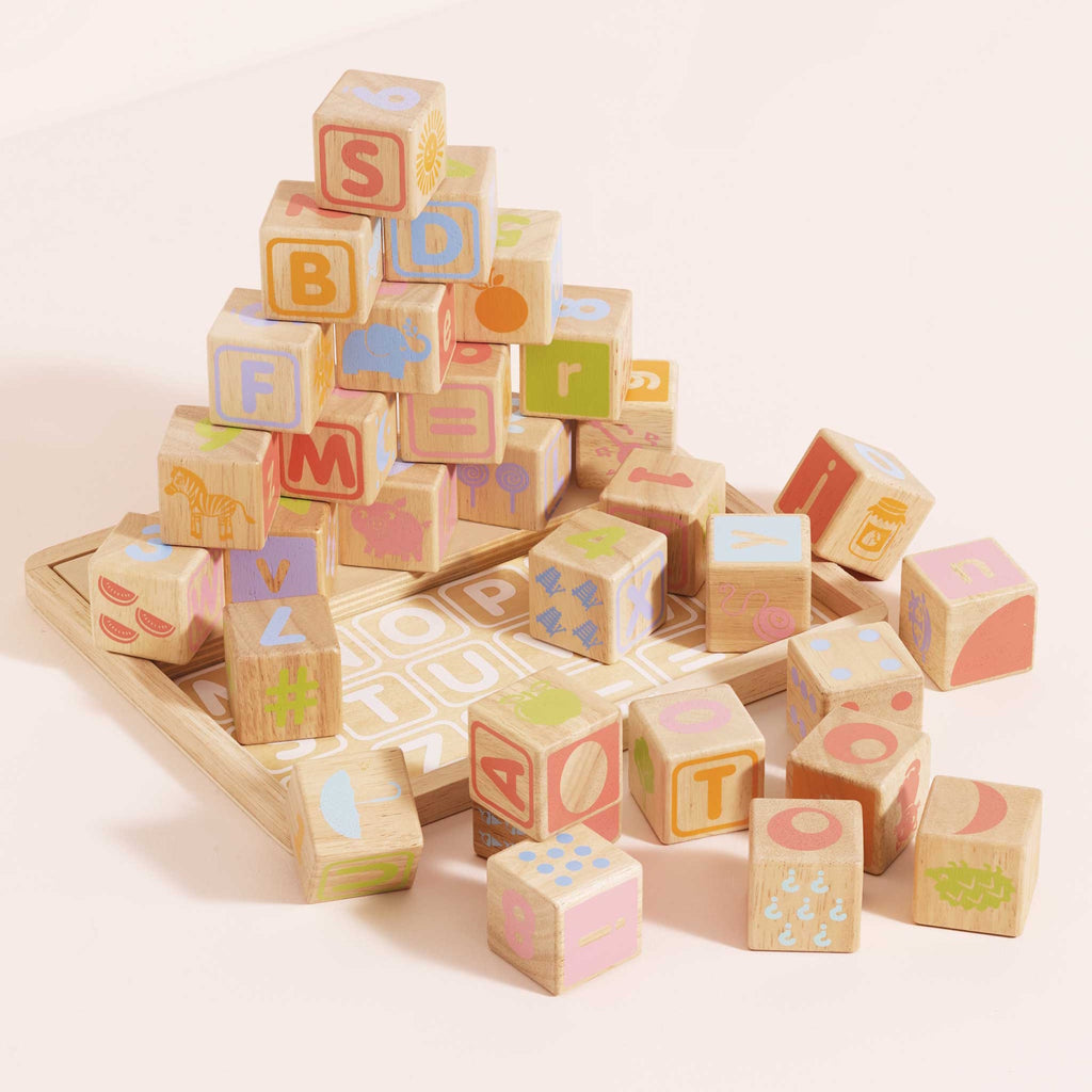 A colorful arrangement of wooden alphabet blocks, featuring letters and playful designs, scattered around a wooden tray.