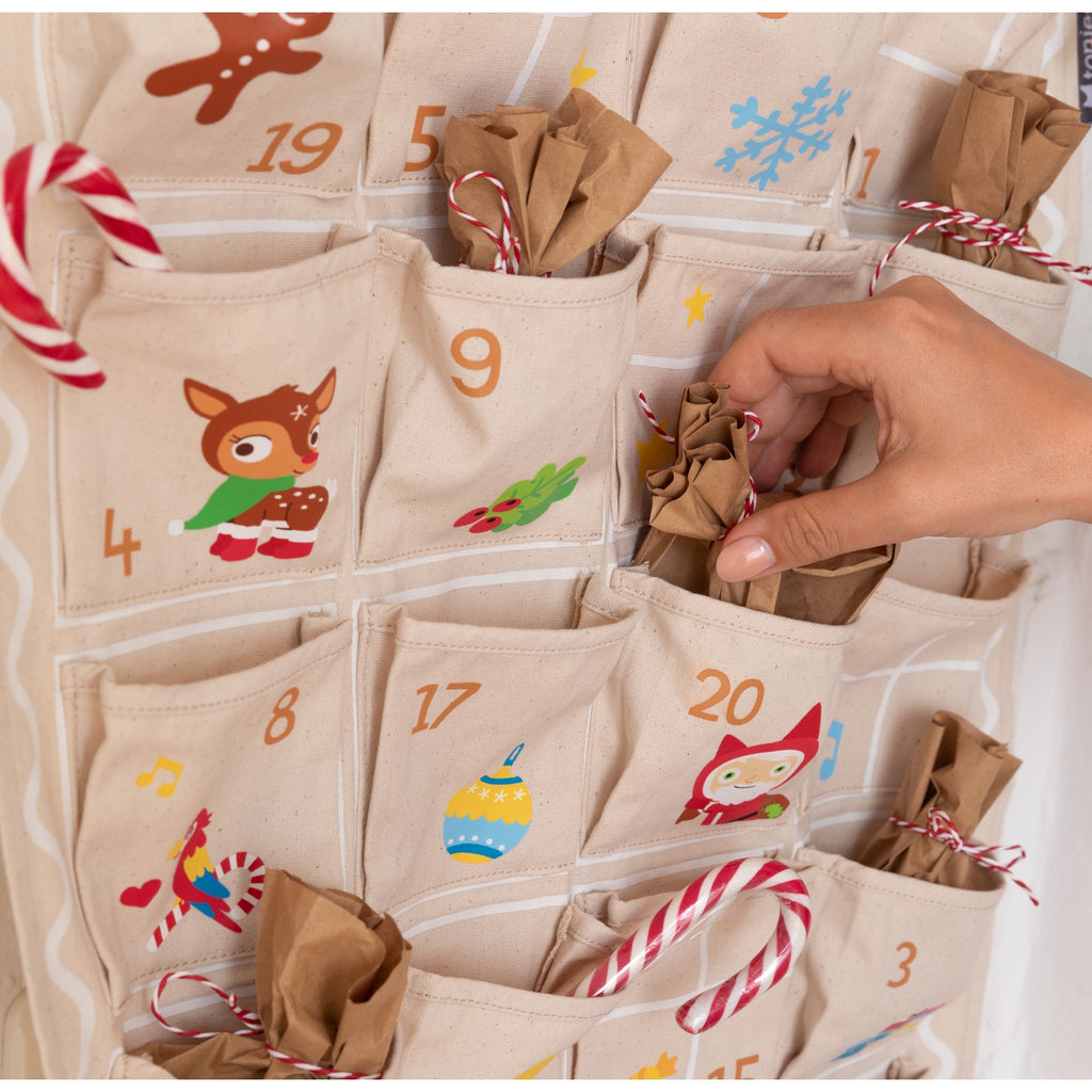 A festive fabric advent calendar with numbered pockets, featuring cheerful holiday-themed illustrations and a house-shaped design.